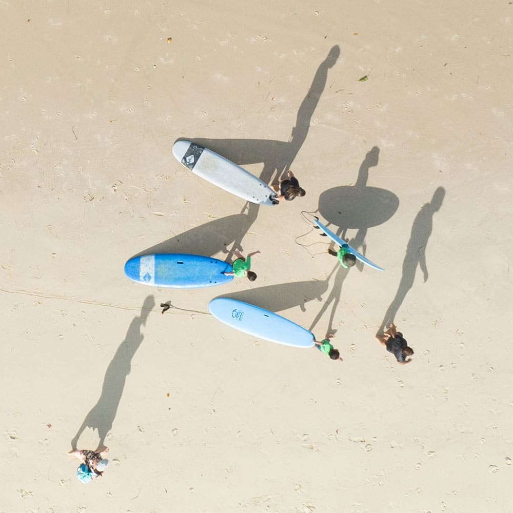 Group of people in the beach carrying surf boards