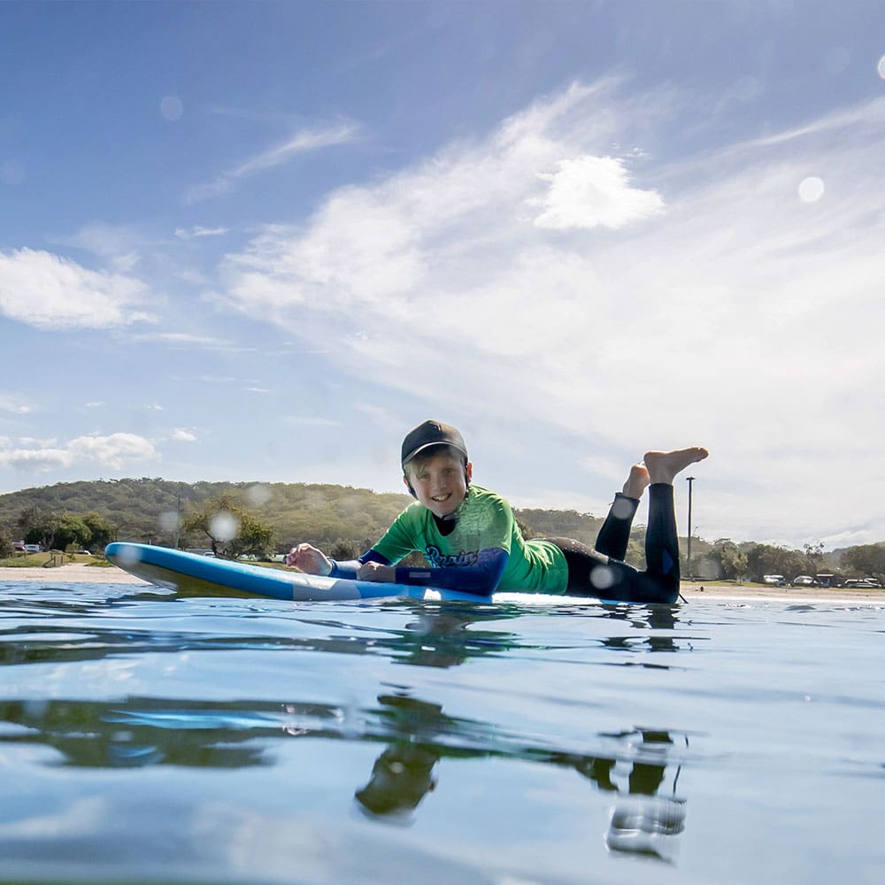 smiling boy on blue surf board